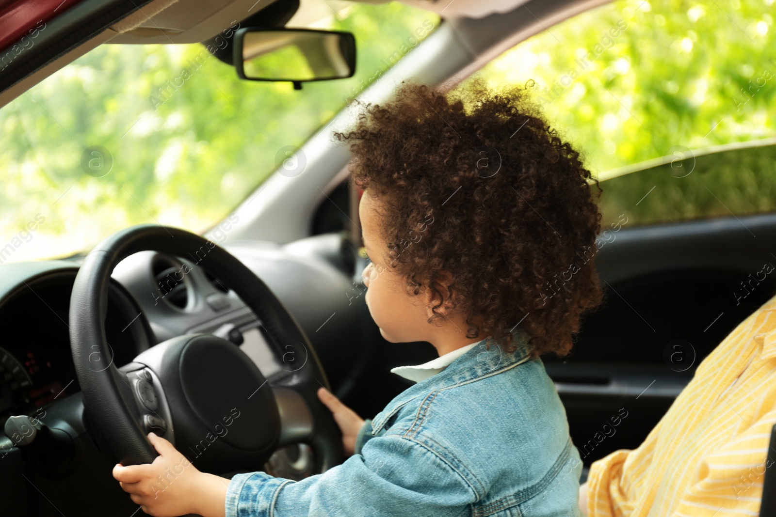 Photo of Mother with cute little daughter driving car together. Child in danger