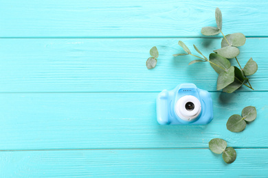 Photo of Toy camera and eucalyptus on light blue wooden background, top view. Space for text
