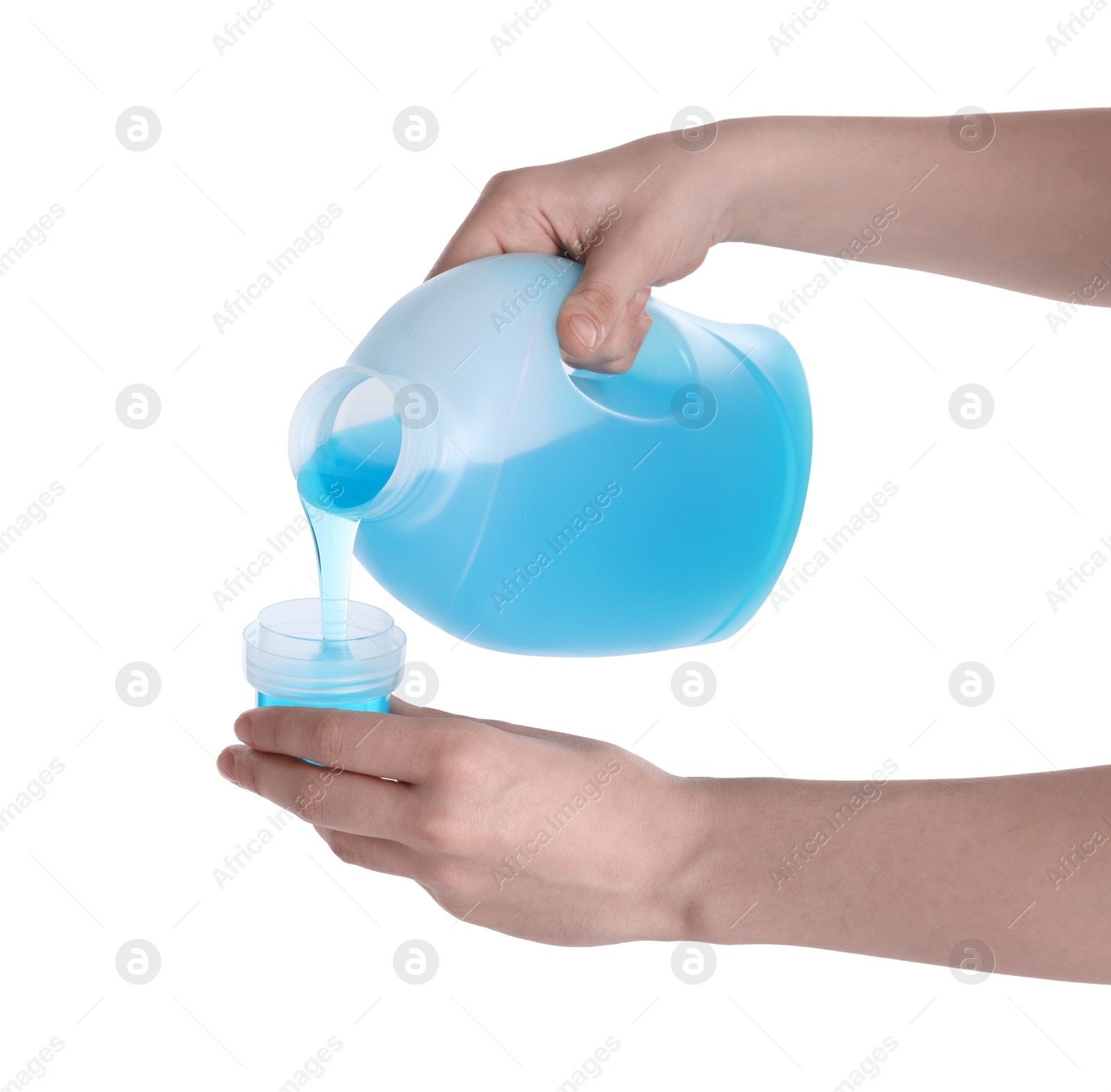 Photo of Woman pouring fabric softener from bottle into cap on white background, closeup