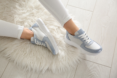 Photo of Woman wearing comfortable stylish sneakers indoors, closeup