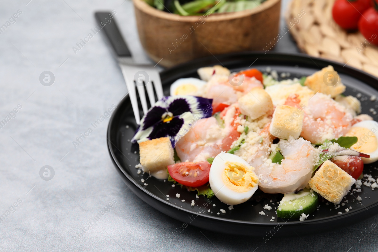 Photo of Delicious Caesar salad with shrimps served on grey table, closeup