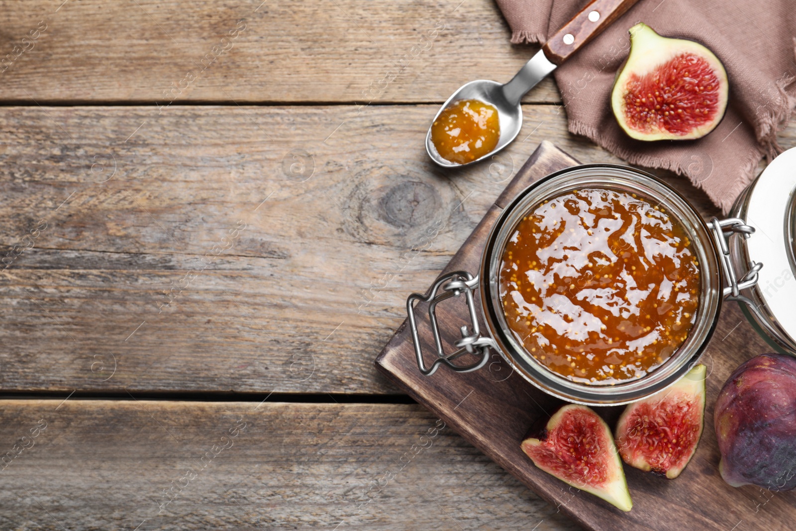 Photo of Flat lay composition with homemade delicious fig jam on wooden table. Space for text