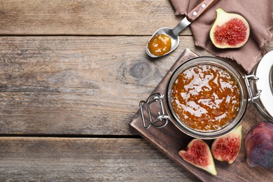 Flat lay composition with homemade delicious fig jam on wooden table. Space for text