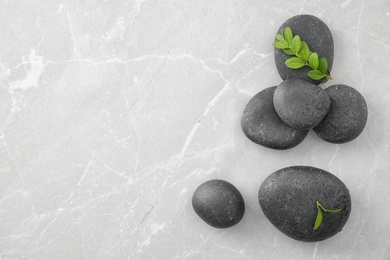 Photo of Spa stones and green leaves on grey table, flat lay with space for text