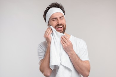 Photo of Washing face. Man with headband and towel on light grey background