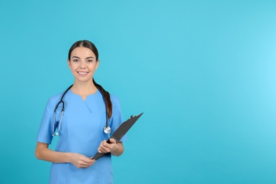 Photo of Portrait of medical assistant with stethoscope and clipboard on color background. Space for text