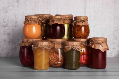 Photo of Many glass jars with different preserved products on wooden table