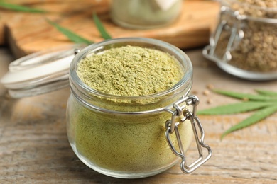 Photo of Jar of hemp protein powder on wooden table, closeup