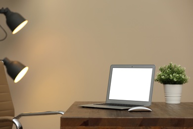 Photo of Laptop with blank screen on table indoors. Space for text