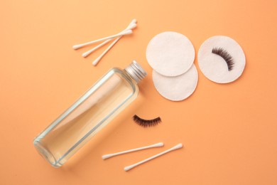 Flat lay composition with makeup remover and false eyelashes on pale orange background
