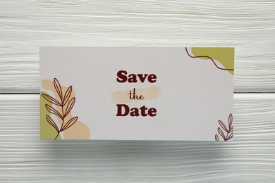 Photo of Beautiful card with Save the Date phrase on white wooden background, top view