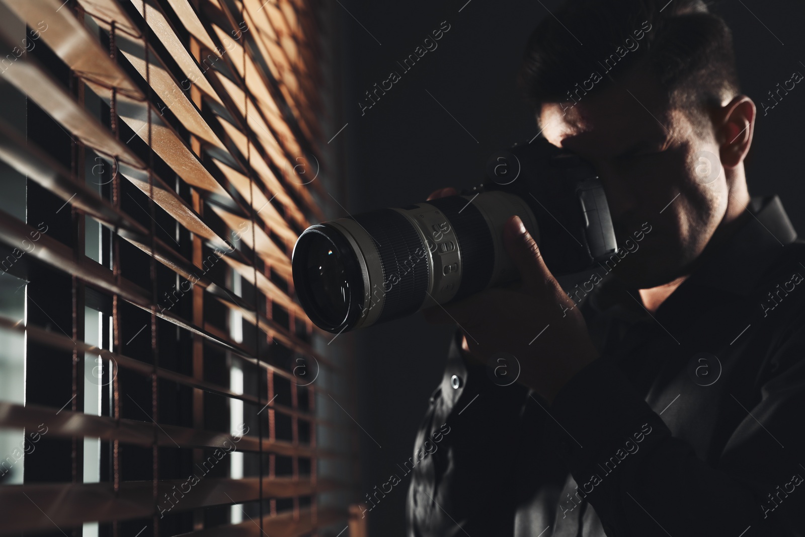 Photo of Private detective with camera spying near window indoors