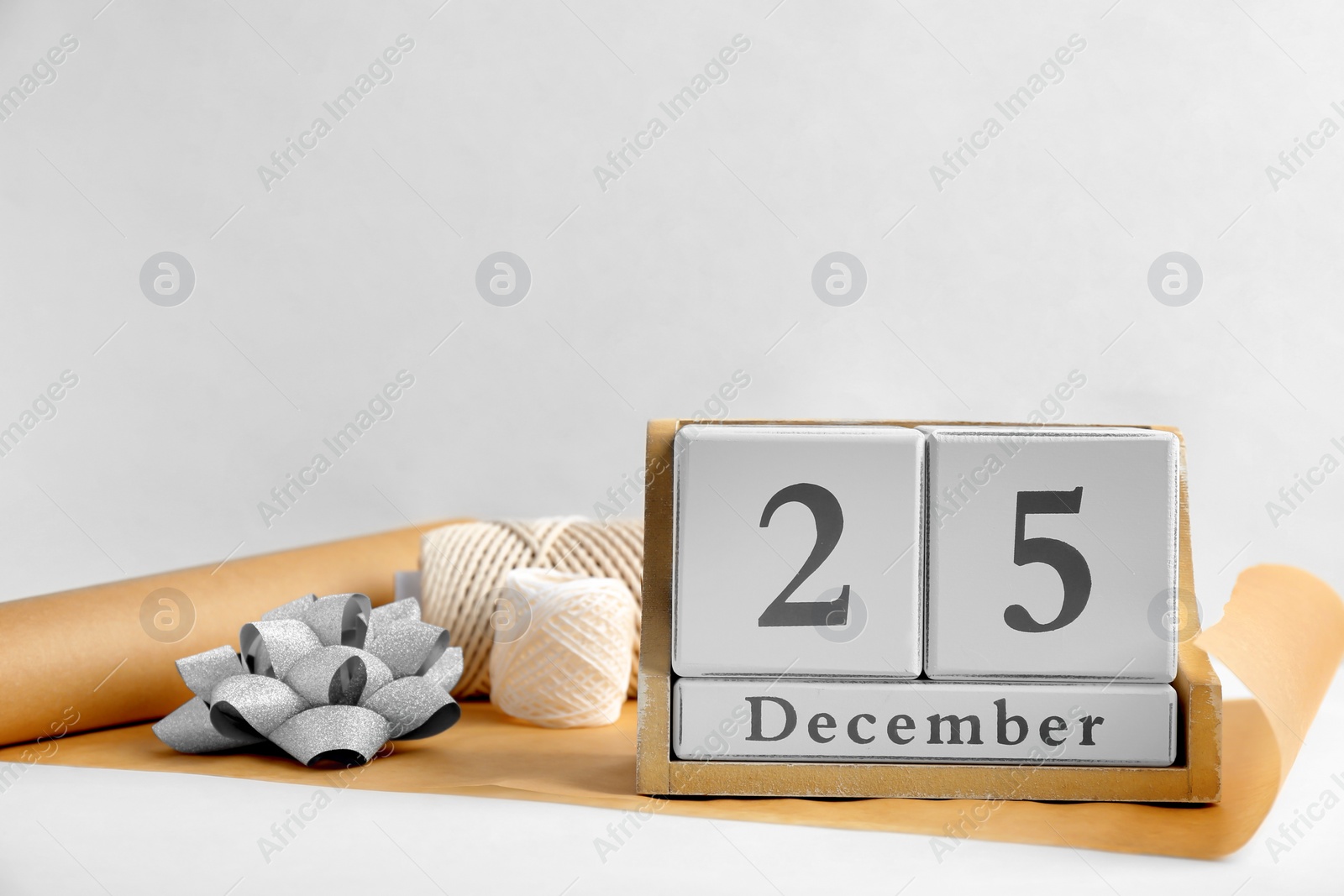 Photo of Wooden block calendar and wrapping supplies on light background. Christmas countdown