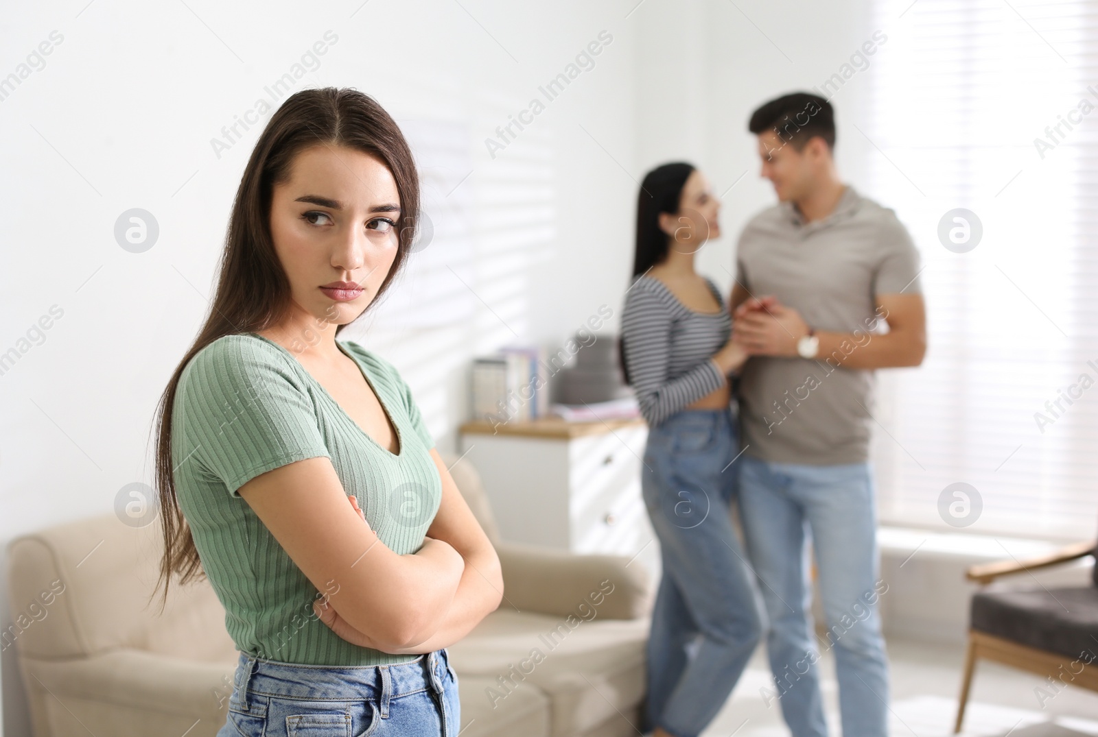 Photo of Unhappy woman feeling jealous while couple spending time together at home