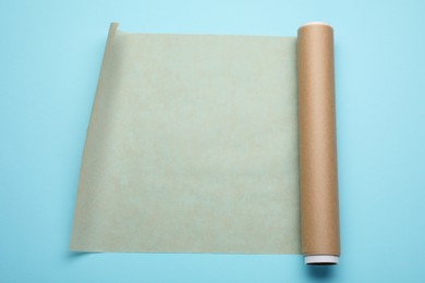 Photo of Roll of baking paper on light blue background, top view