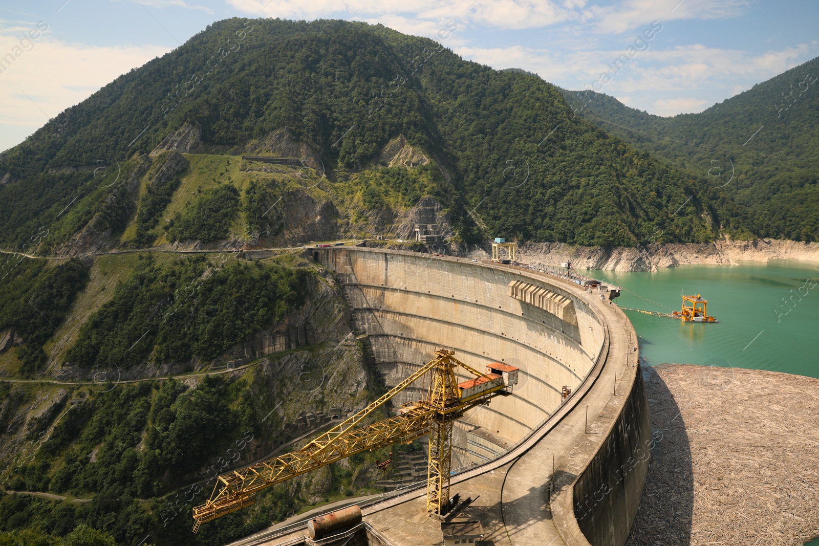 Photo of BATUMI, GEORGIA - AUGUST 13, 2022: Tower crane and hydroelectric power station in mountains