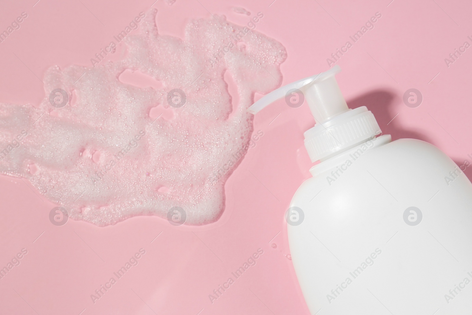 Photo of Dispenser with cleansing foam on pink background, flat lay. Cosmetic product