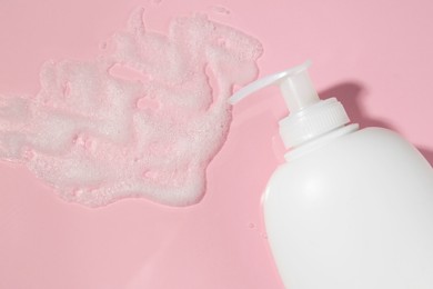 Dispenser with cleansing foam on pink background, flat lay. Cosmetic product