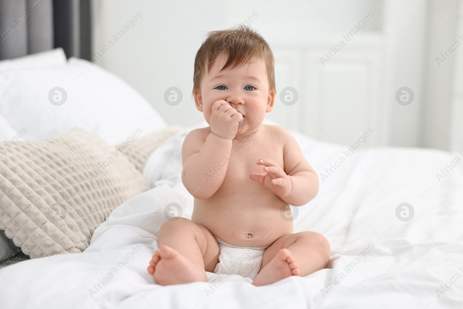 Photo of Cute baby boy sitting on bed at home