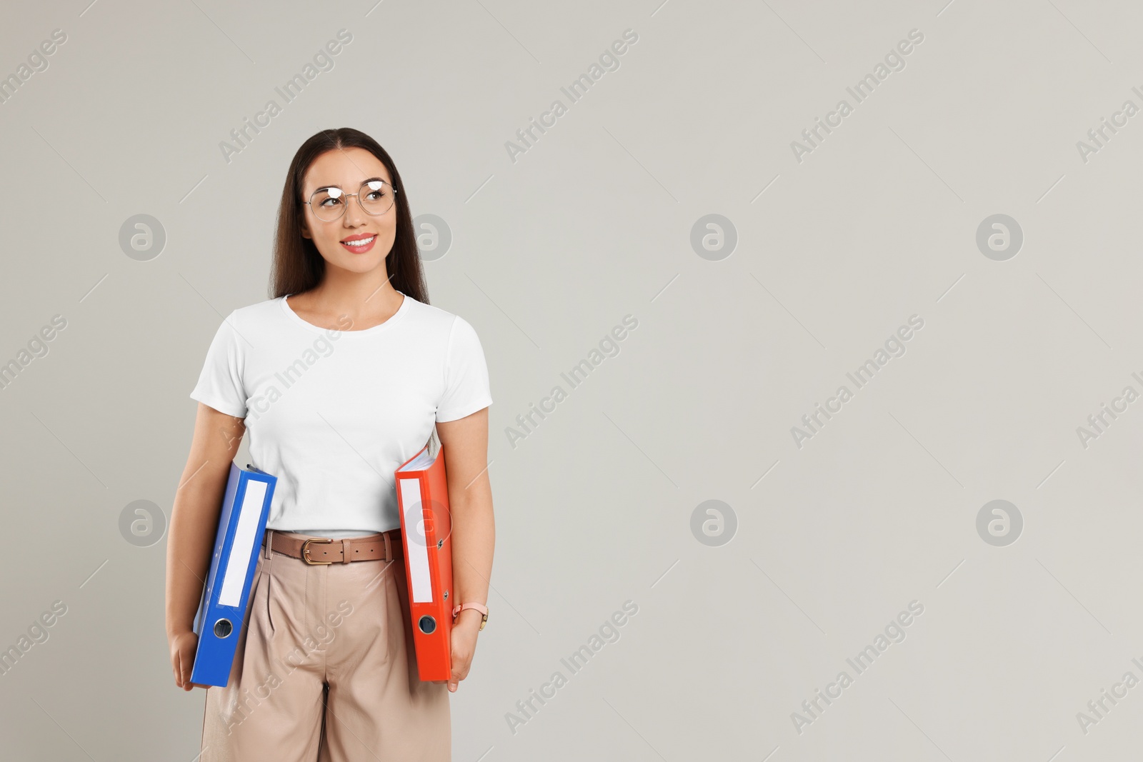 Photo of Happy woman with folders on light gray background, space for text