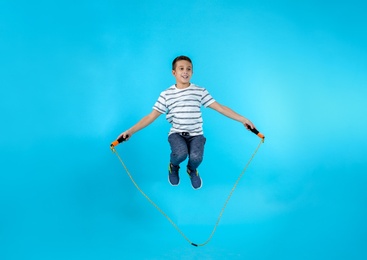 Full length portrait of boy jumping rope on color background