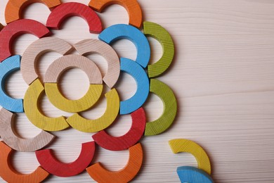 Photo of Colorful wooden pieces of educational toy on light table, flat lay and space for text. Motor skills development