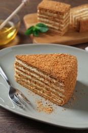 Photo of Slice of delicious layered honey cake served on wooden table, closeup