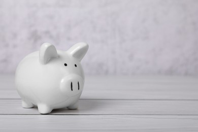 Photo of Ceramic piggy bank on white wooden table, space for text. Financial savings