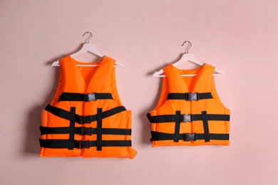 Orange life jackets on pink background. Personal flotation device