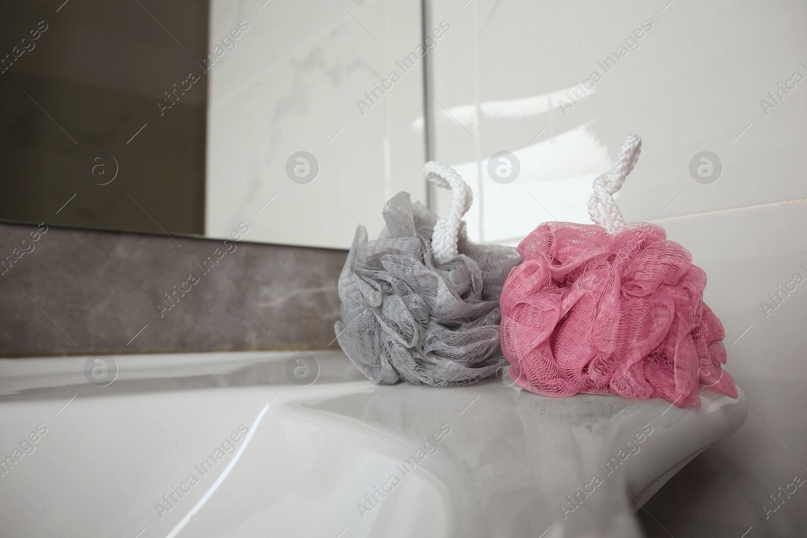 Photo of Colorful shower puffs on sink in bathroom, space for text