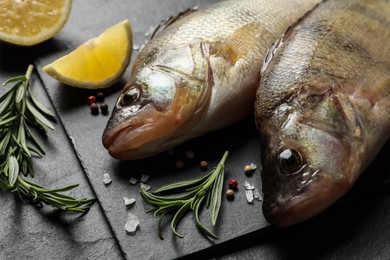 Photo of Fresh raw perches and ingredients on black slate table, closeup. River fish