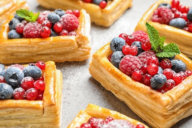 Fresh delicious puff pastry with sweet berries on grey table, closeup