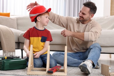 Photo of Father putting hard hat on his son at home. Repair work