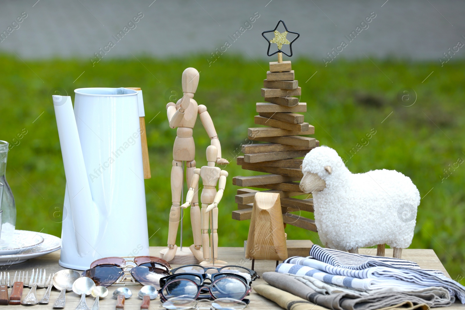 Photo of Many different decorative items on wooden table outdoors. Garage sale