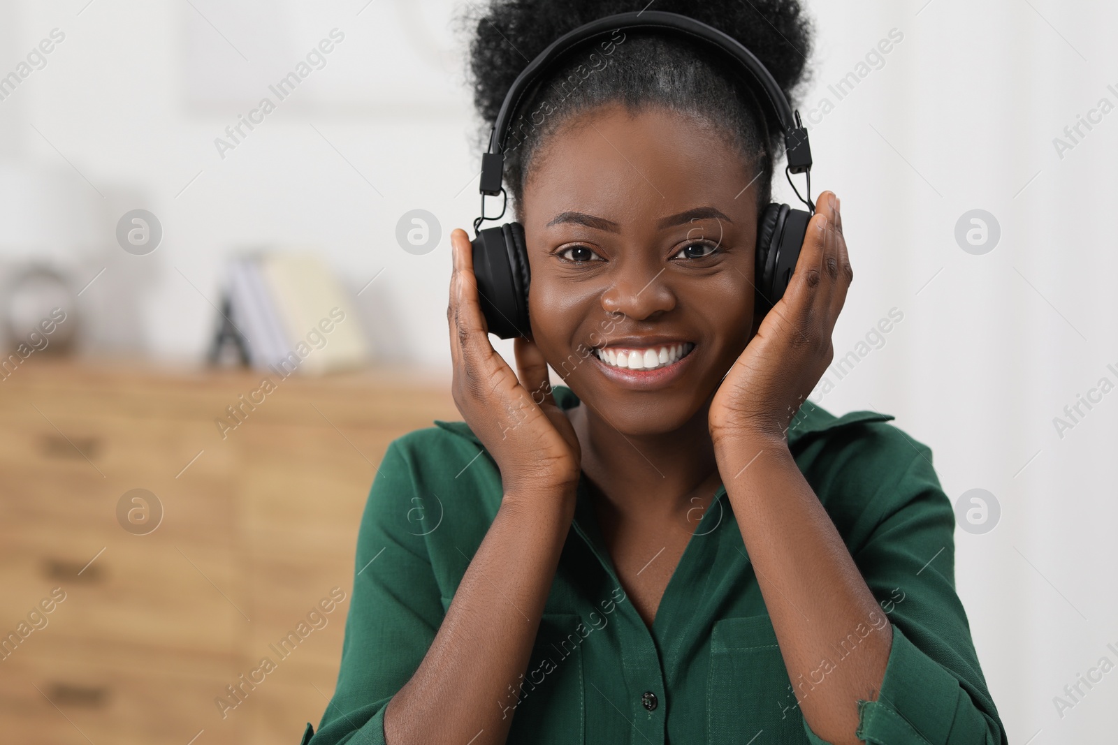 Photo of Beautiful young woman in headphones enjoying music indoors