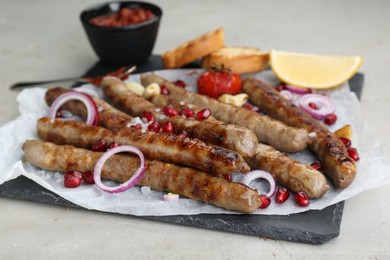 Tasty grilled sausages served on light table, closeup