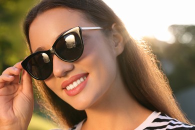 Photo of Beautiful smiling woman in sunglasses outdoors on sunny day