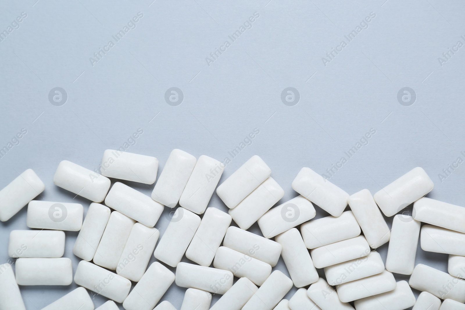 Photo of Tasty white chewing gums on light grey background, flat lay. Space for text