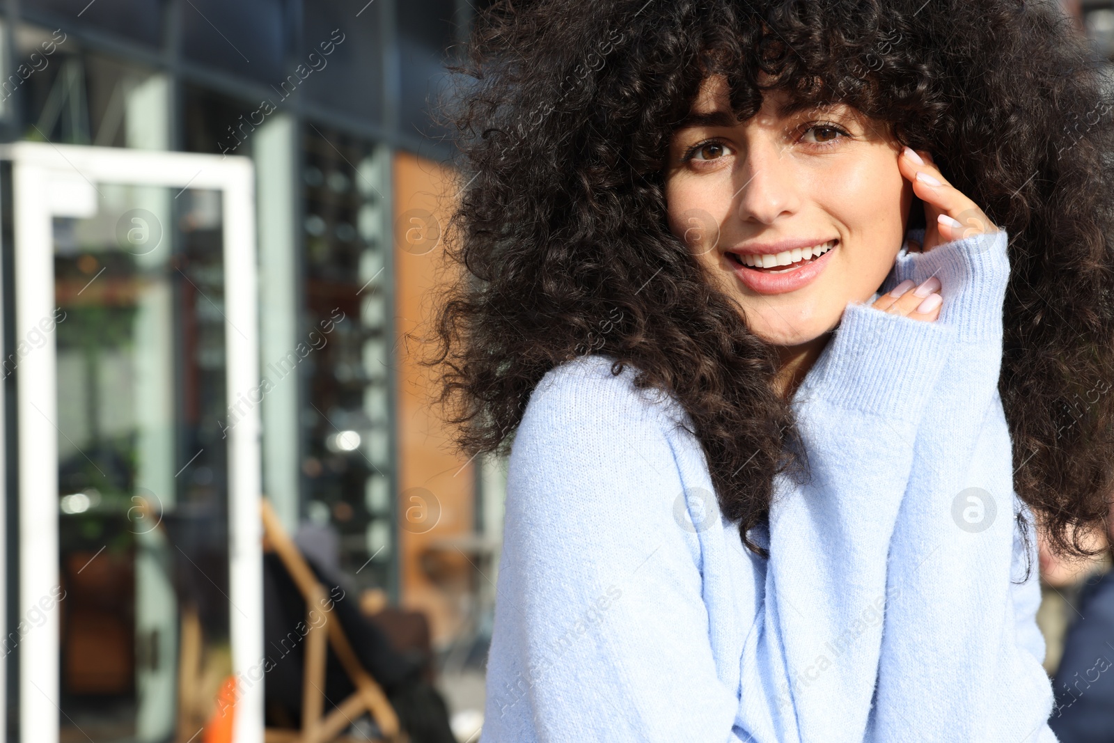 Photo of Happy young woman in stylish light blue sweater outdoors, space for text