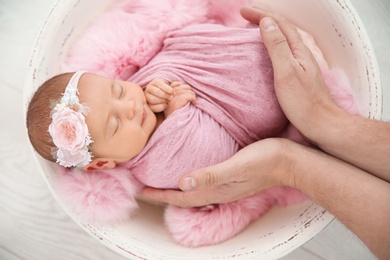 Photo of Cute newborn baby girl with her father on light background, top view