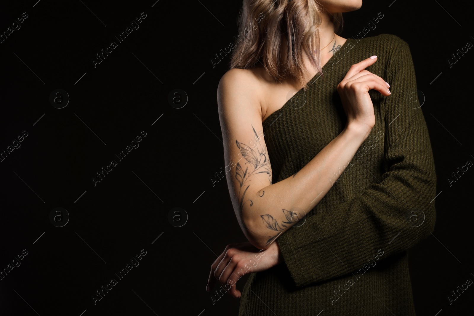 Photo of Beautiful woman with tattoos on body against black background, closeup. Space for text