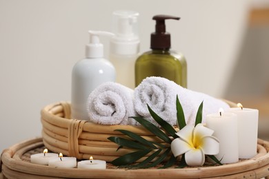 Photo of Spa products, burning candles, plumeria flower and tropical leaf on table, closeup