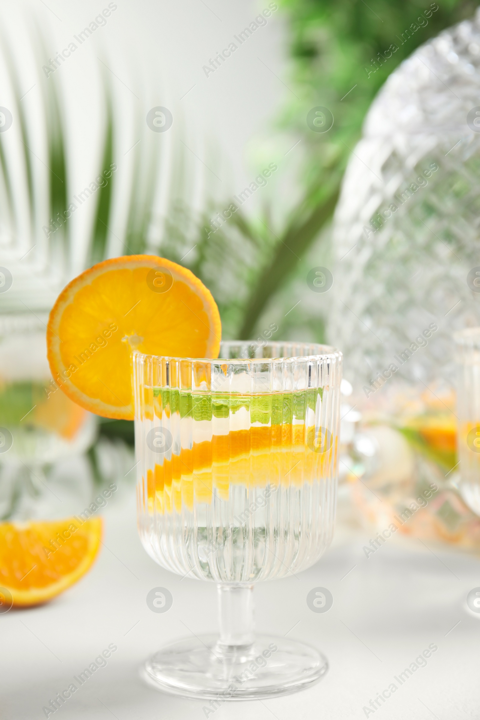 Photo of Delicious refreshing drink with orange and mint on white table