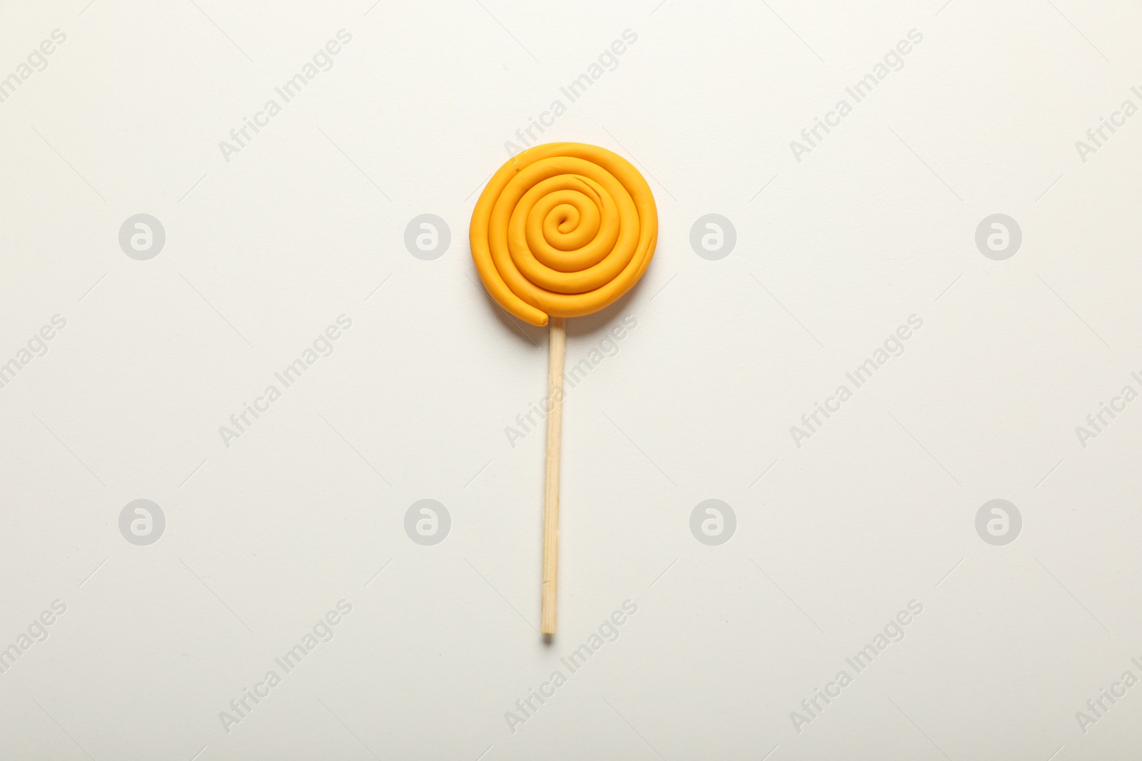 Photo of Yellow lollipop made of plasticine on white background, top view