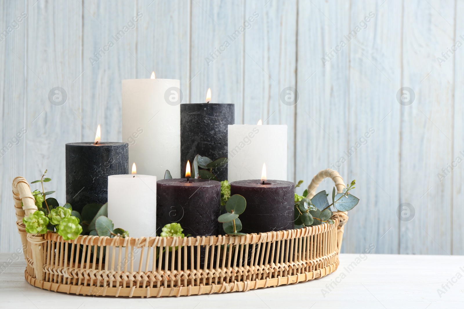 Photo of Tray with burning candles, green branches and flowers on white table, space for text