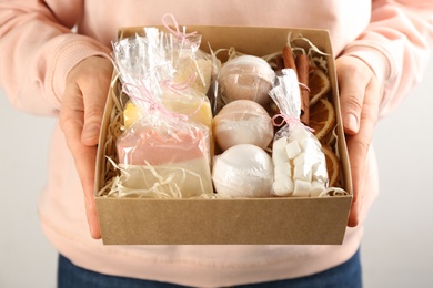 Woman holding box with stylish craft gift set on light grey background, closeup