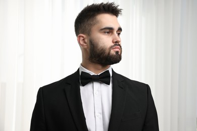 Portrait of handsome man in suit, shirt and bow tie indoors