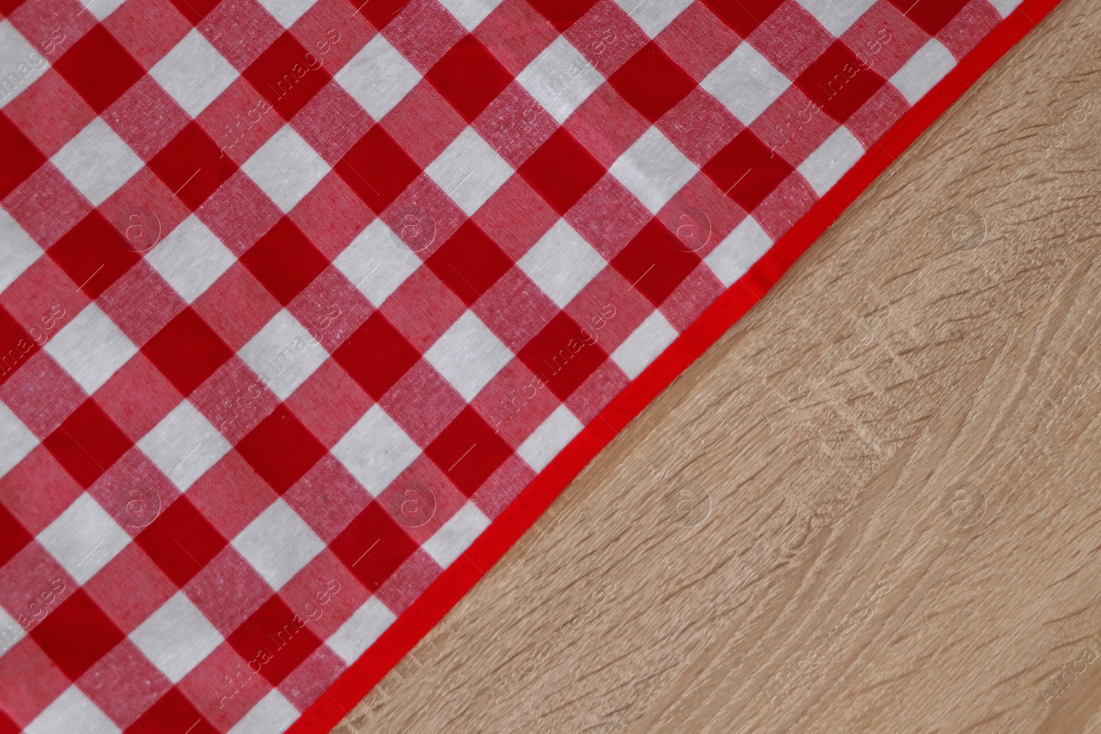 Photo of Checkered picnic cloth on wooden table, top view. Space for text