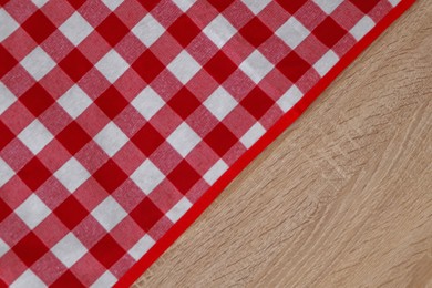 Photo of Checkered picnic cloth on wooden table, top view. Space for text