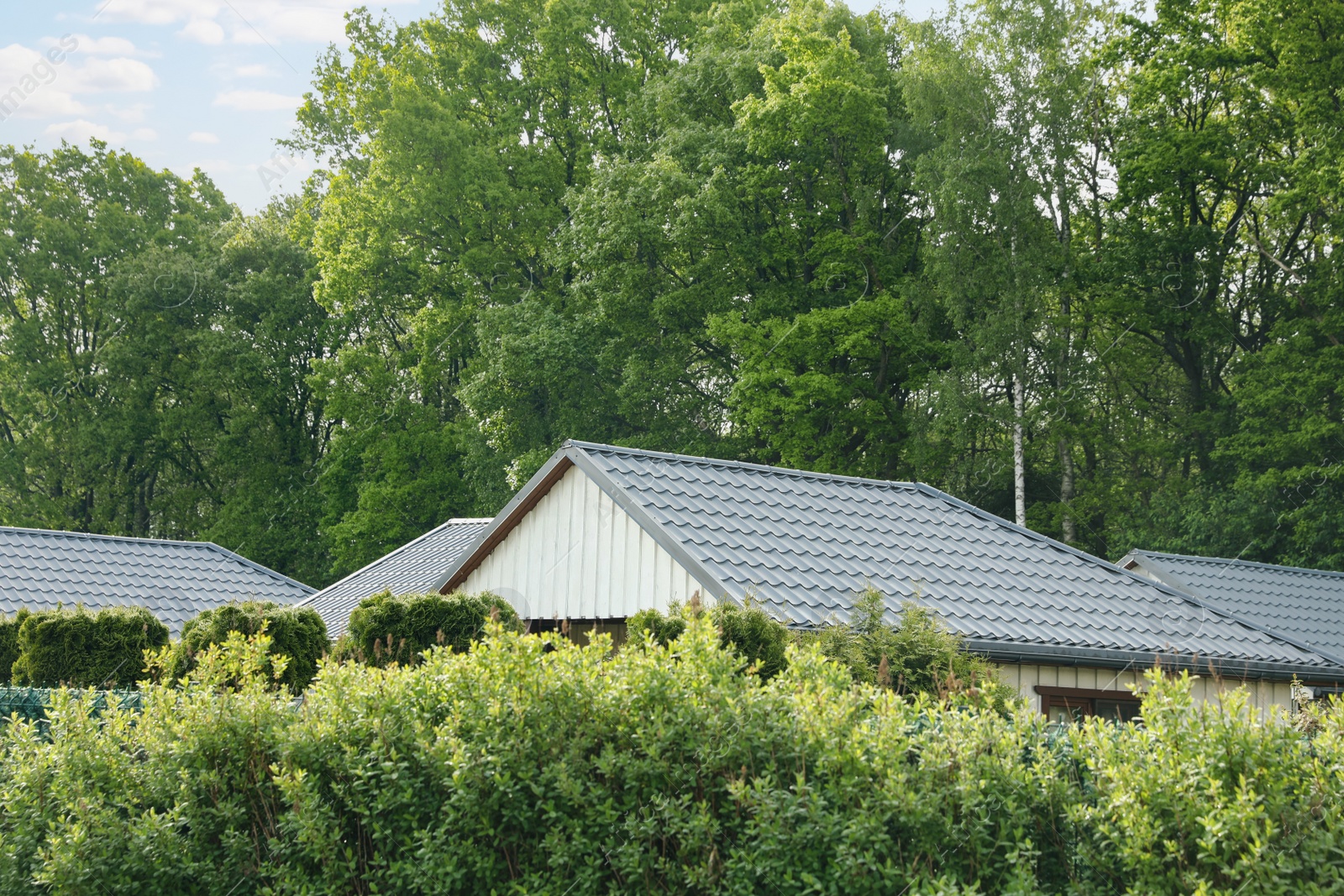 Photo of Modern buildings with grey roofs outdoors on sunny day